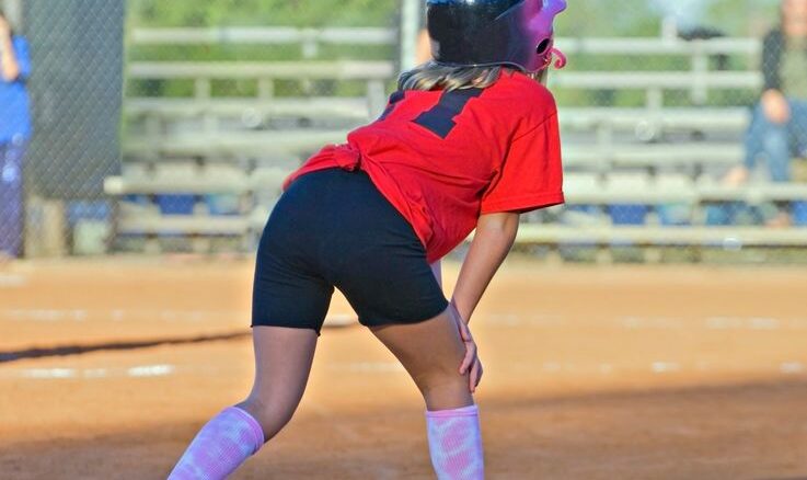 7989529 - a young girl softball player on third base ready to run into home.